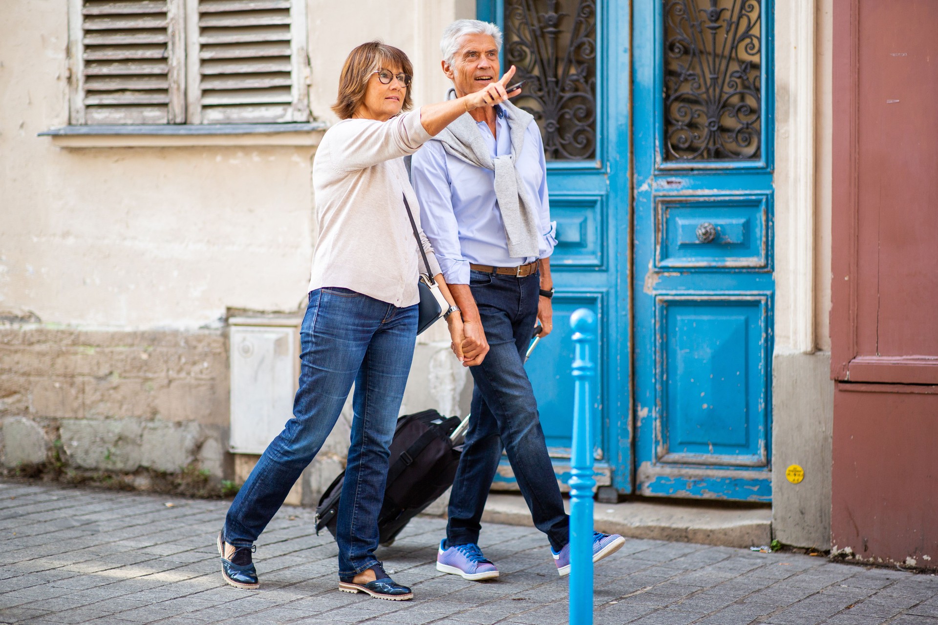 Side of happy couple walking on street with suitcase